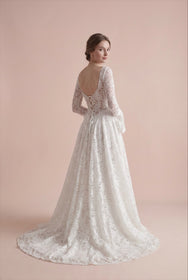 Load image into Gallery viewer, AKAY Gelinlik’e ait uzun kollu dantel A kesim gelinlik modeli. Transparan detaylı üst beden, floral işlemeler ve zarif kuyruk formuyla modern romantik bridal couture tasarım.
