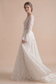 Load image into Gallery viewer, AKAY Gelinlik’e ait uzun kollu dantel A kesim gelinlik modeli. Transparan detaylı üst beden, floral işlemeler ve zarif kuyruk formuyla modern romantik bridal couture tasarım.
