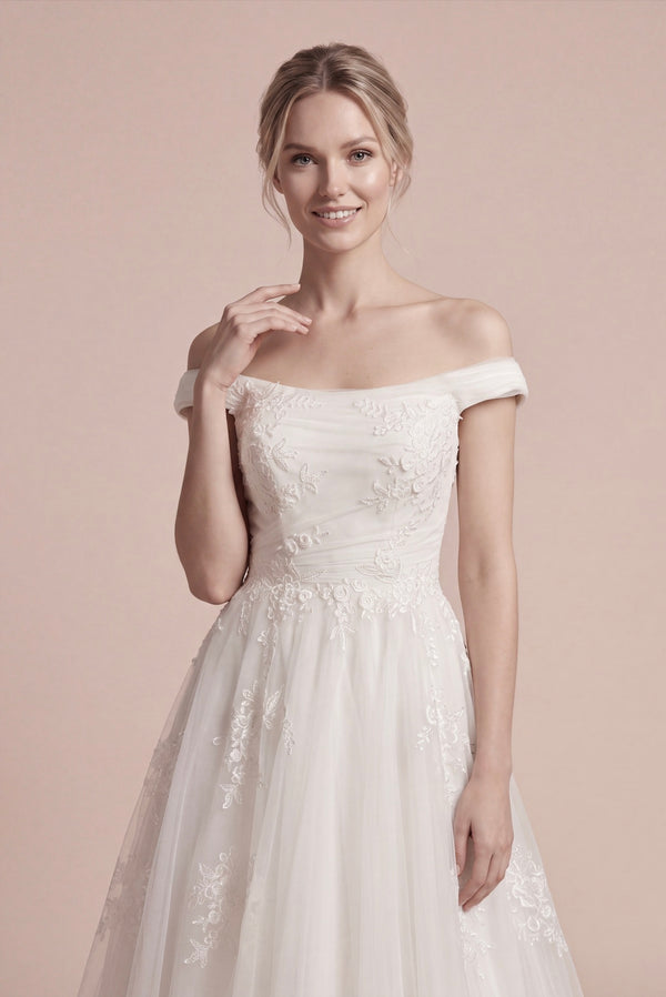 Düşük omuzlu, dantel aplikeli korsaj ve tül A kesim eteğe sahip romantik gelinlik modeli.